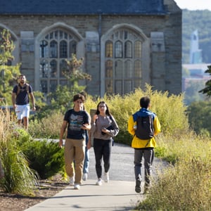 A group of people walking down a sidewalk. A group of people walking down a sidewalk.