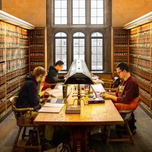 A group of people sitting at a table in a library. A group of people sitting at a table in a library.