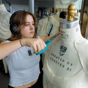 A woman is cutting a dress on a mannequin. A woman is cutting a dress on a mannequin.