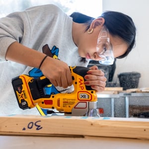 A woman is using a saw to cut wood. A woman is using a saw to cut wood.