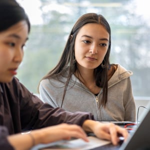 Two women sitting at a table looking at a laptop. Two women sitting at a table looking at a laptop.